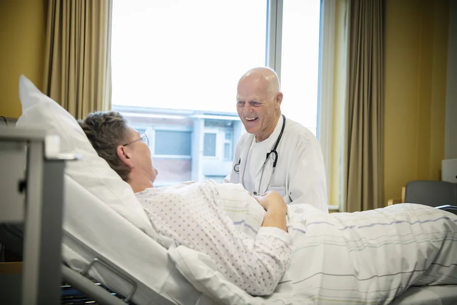 Lege snakker pasient i seng
