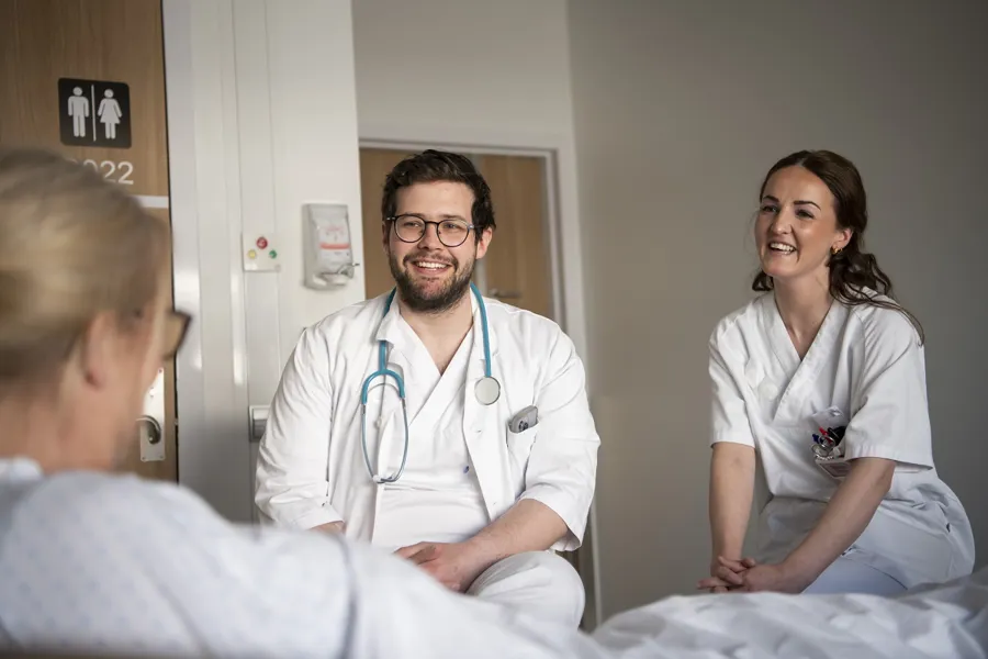 En mannlig og kvinnelig lege snakker med en pasient