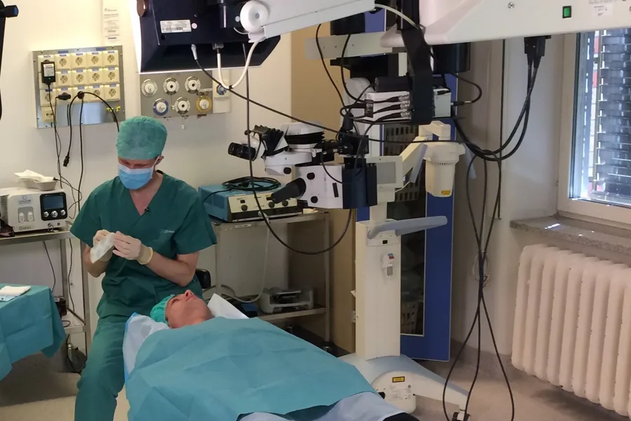 En person i kirurgisk skrubb som tar seg av en pasient