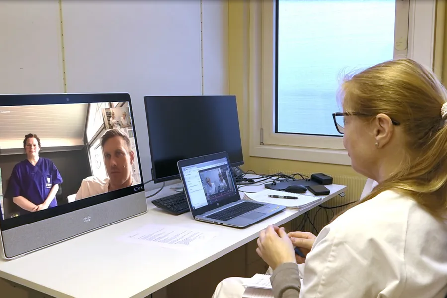 En kvinne i hvit frakk sitter ved et skrivebord og ser på en dataskjerm