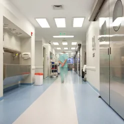 Foto av en mann i grønn klinikerdrakt som går i en sykehuskorridor.