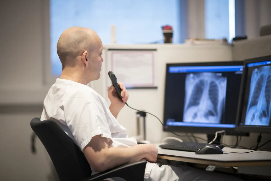 Mann med diktafon leser inn informasjon fra røntgenbilder
