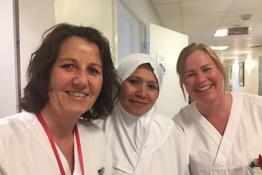 En gruppe kvinner iført hvite labfrakker og smilende