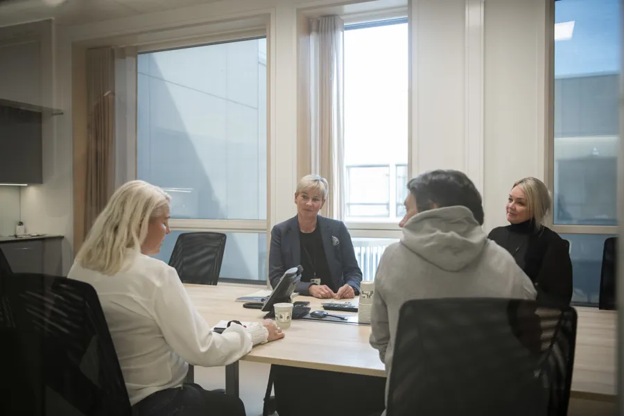 Fire mennesker rundt et møtebord